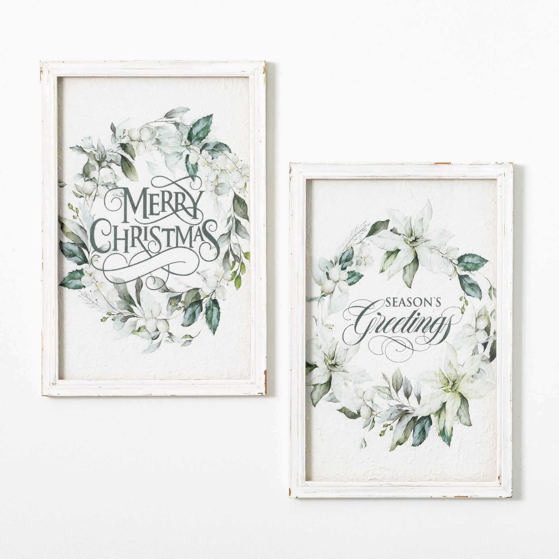 both styles of poinsettia wall decor have a white frame with a pale green and white flower wreath in the center with different sentiments in each and displayed against a white background