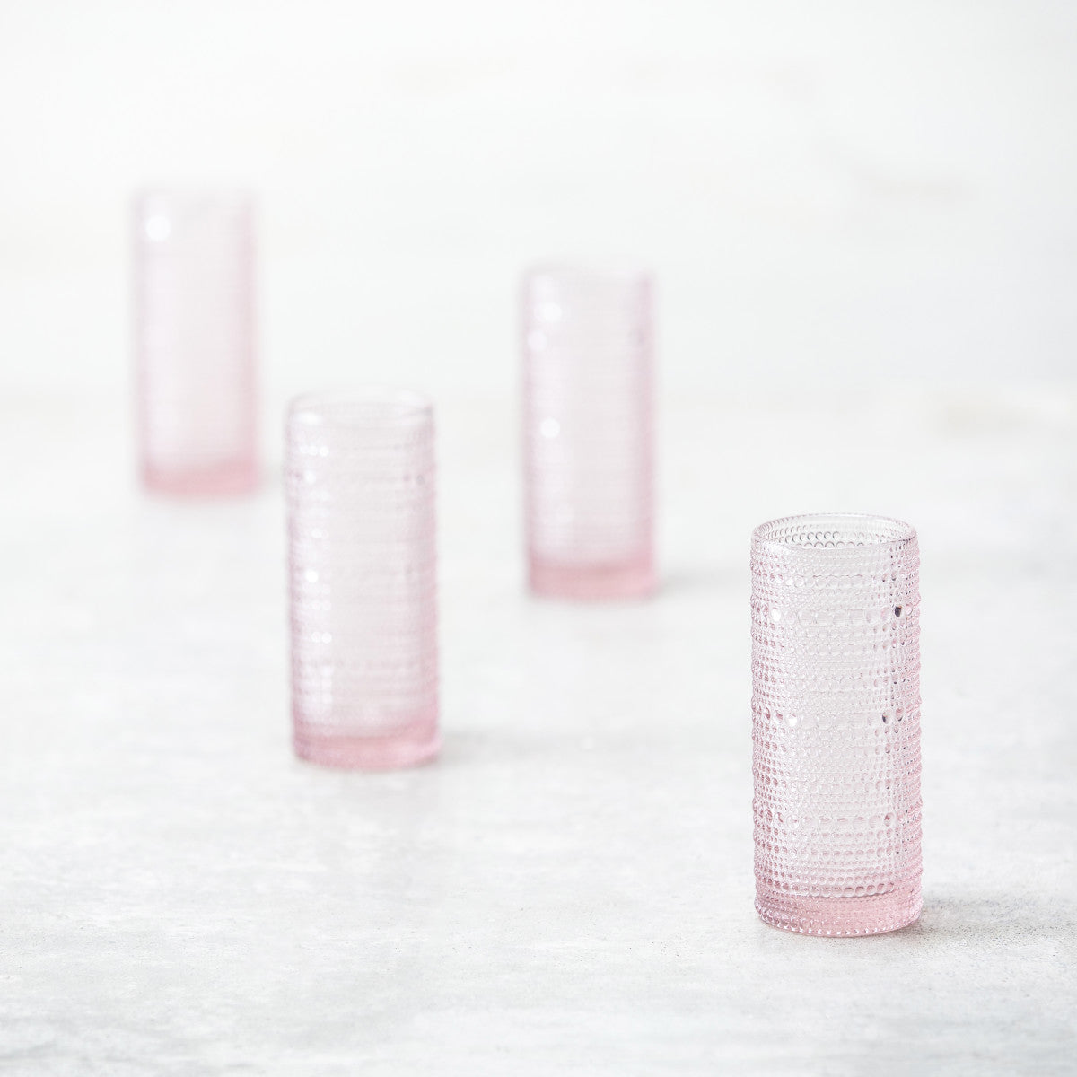 4 pink jupiter collins glasses arranged on a countertop.