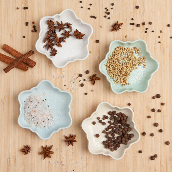 top view of 4 snowflake dishes on a table with spices acattered about.