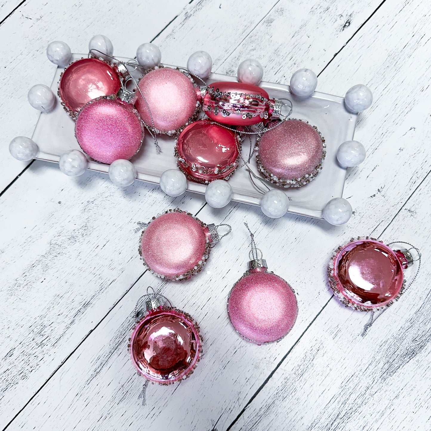 Set of various styles pink macaroon ornaments on a wooden table and in a ceramic dish.