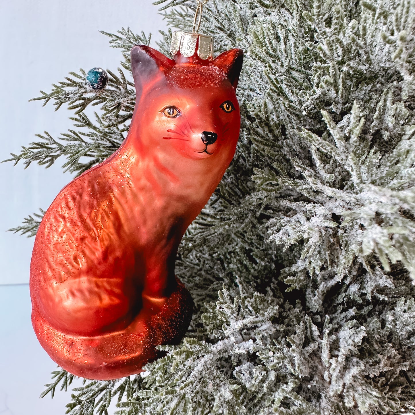 Fox shaped ornament hanging in a tree.