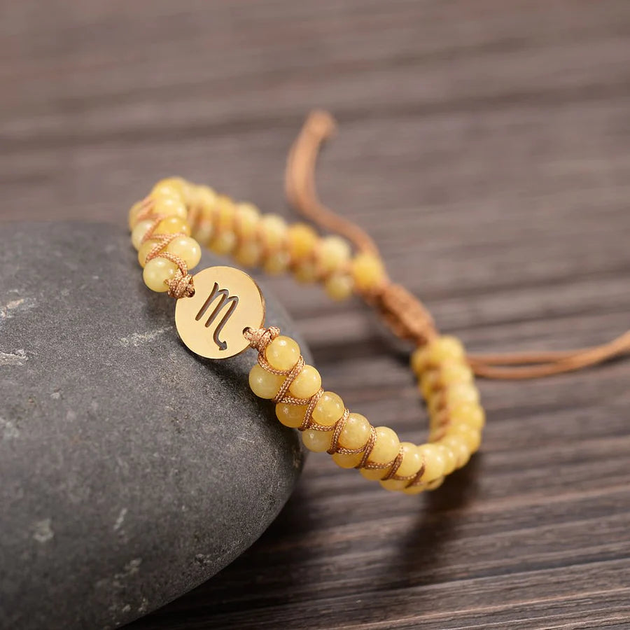 Scorpio bracelet draped on a stone on a wooden table.
