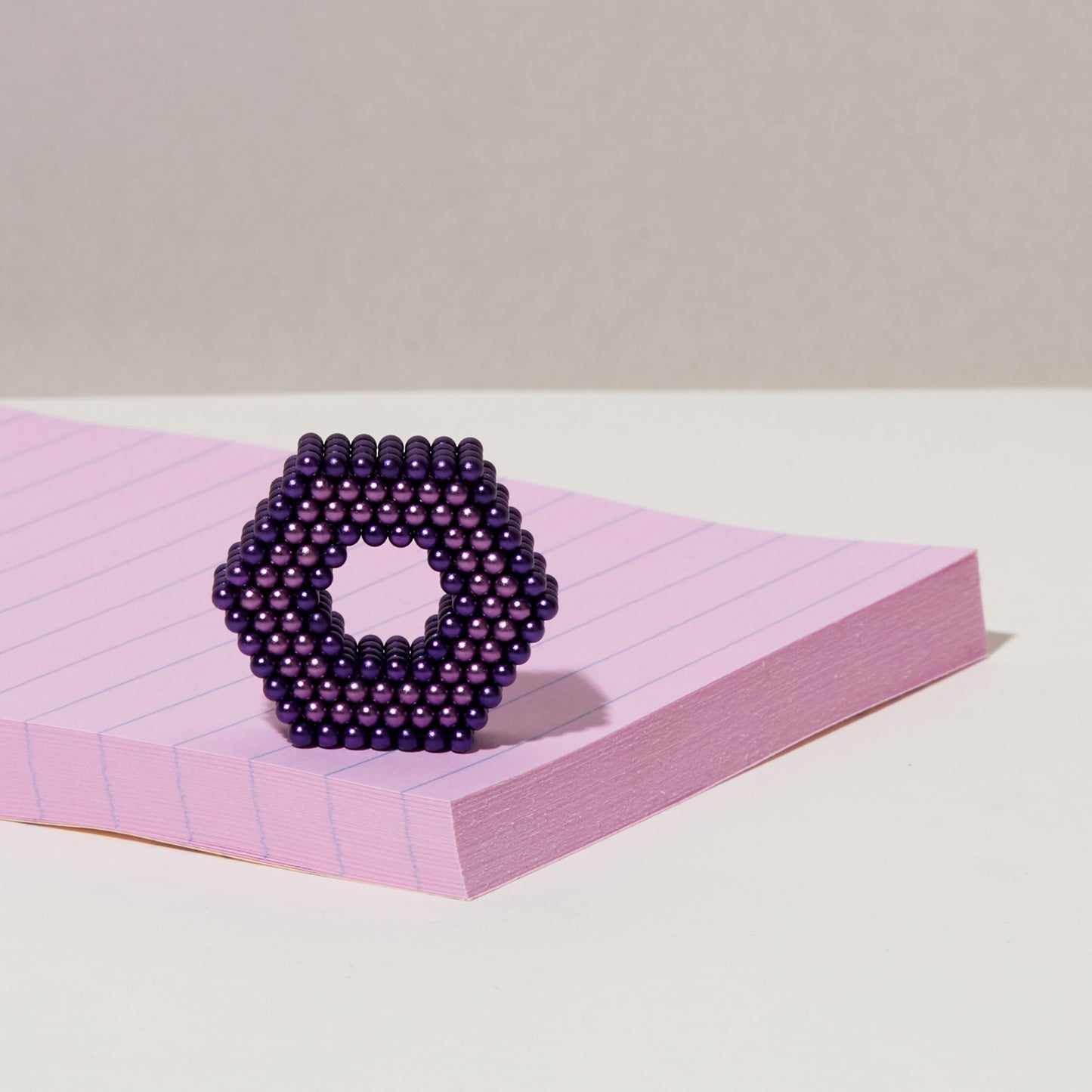 magnetic balls in vary shades of purple formed into a geometric shape set on a pad of paper