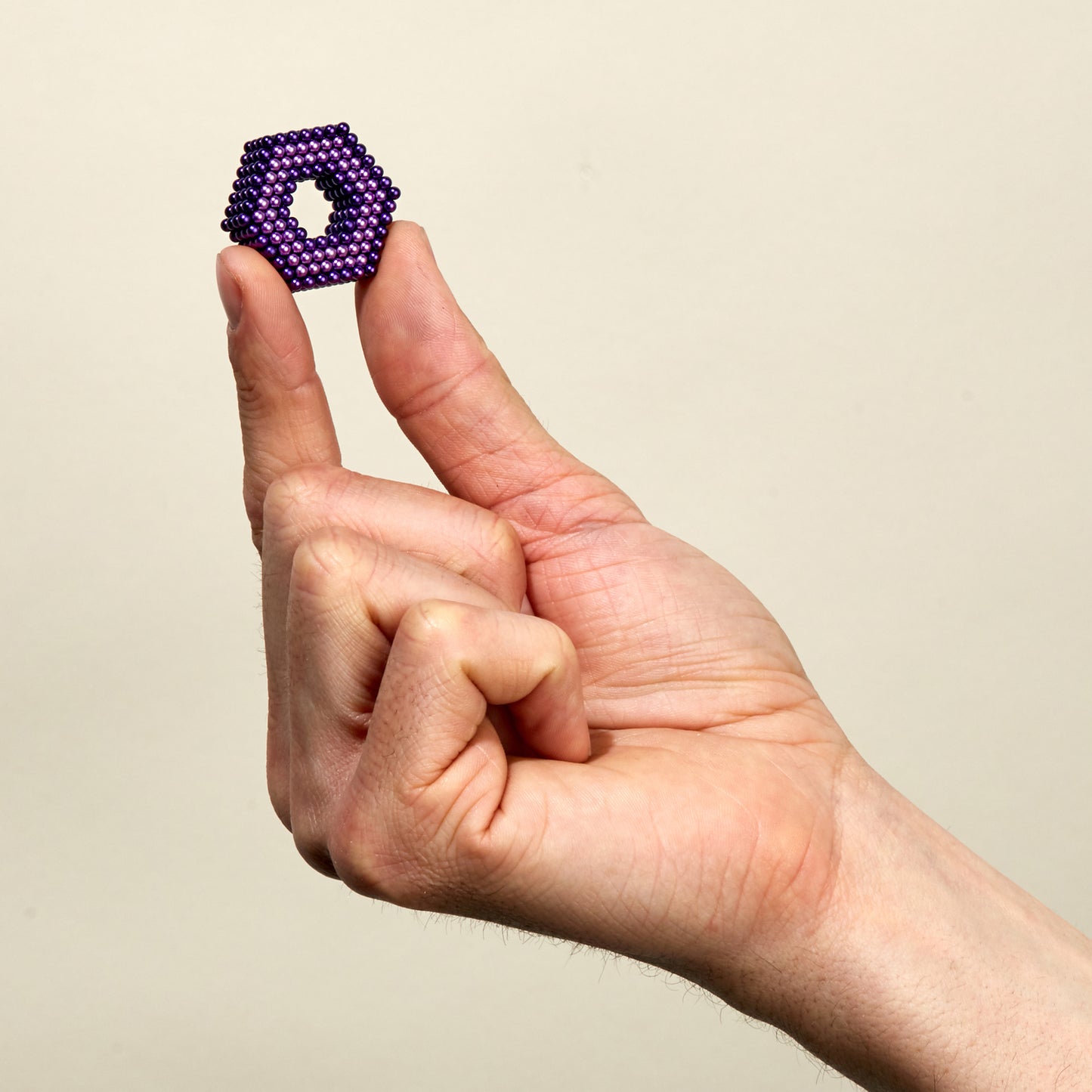 hand holding shape made of tones haze colored magnetic balls