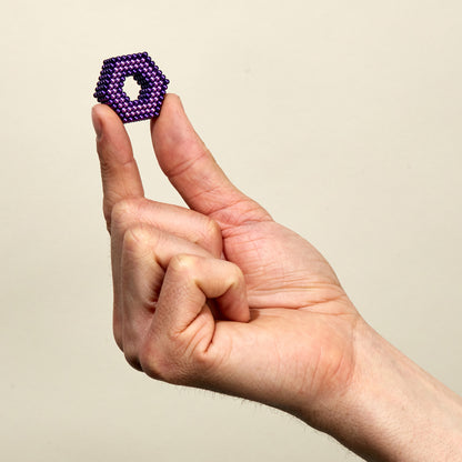 hand holding shape made of tones haze colored magnetic balls