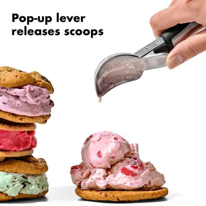 hand using ice cream scoop with lever to put ice cream on a cookie.