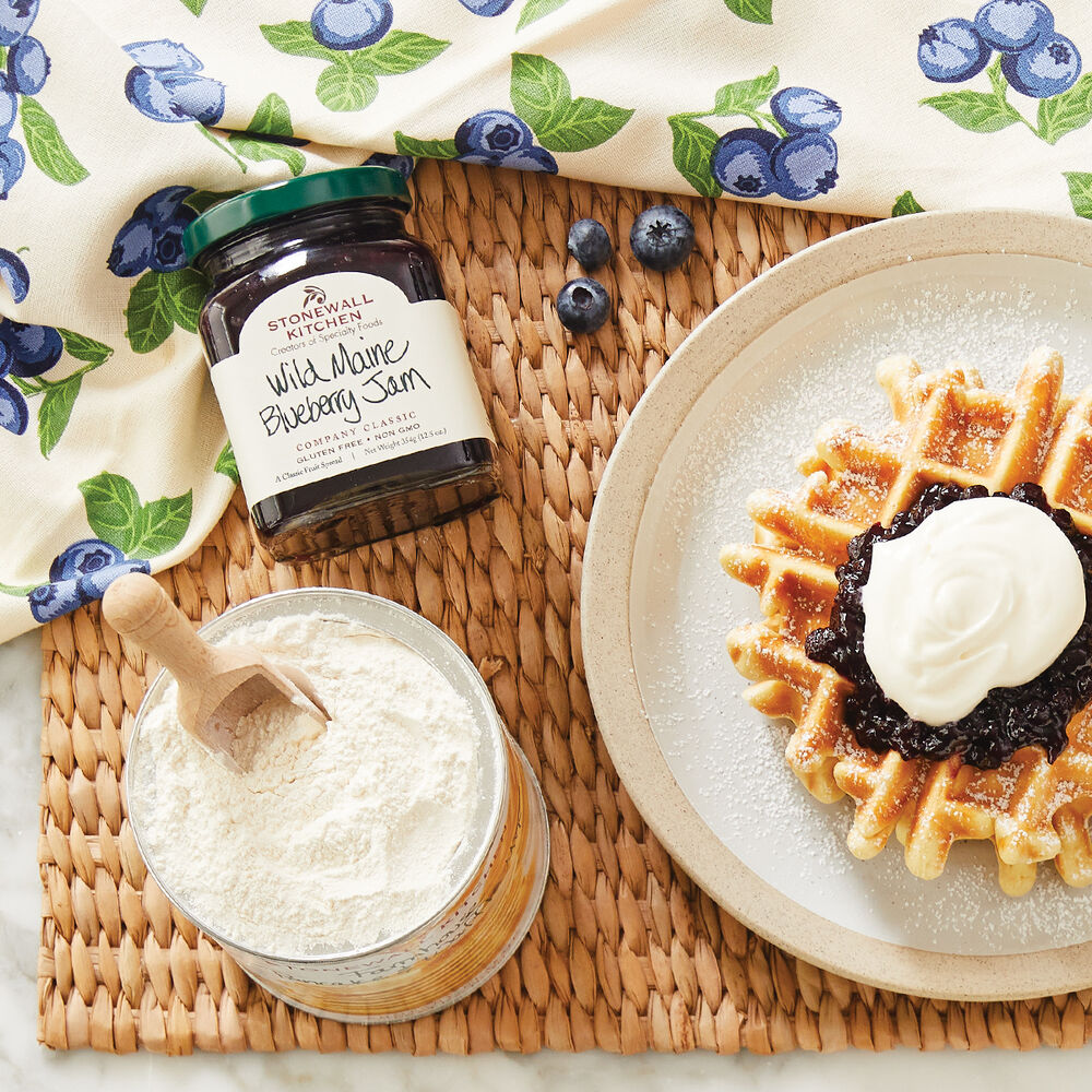 top view of a table arranged with Wild Maine Blueberry Jam, a plate of waffles, and a jar of pawdered sugar.