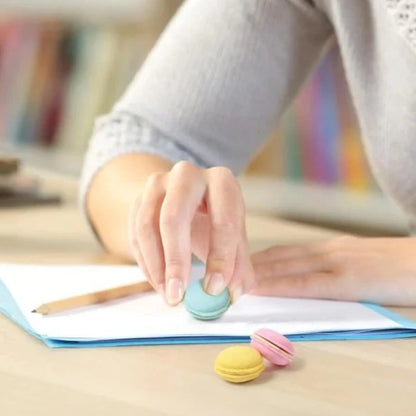 person sitting a desk using macaron erasers.