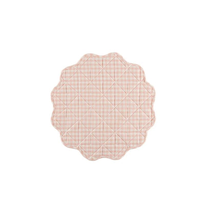 Pink quilted placemat with scalloped edge on a white background