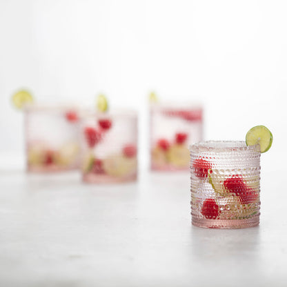 4 pink jupiter double old fashion glasses filled with beverage and garnished with fruit. 