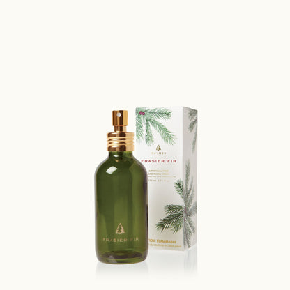 Green bottle of fraiser fir tree and room spray in front of its box on a white background
