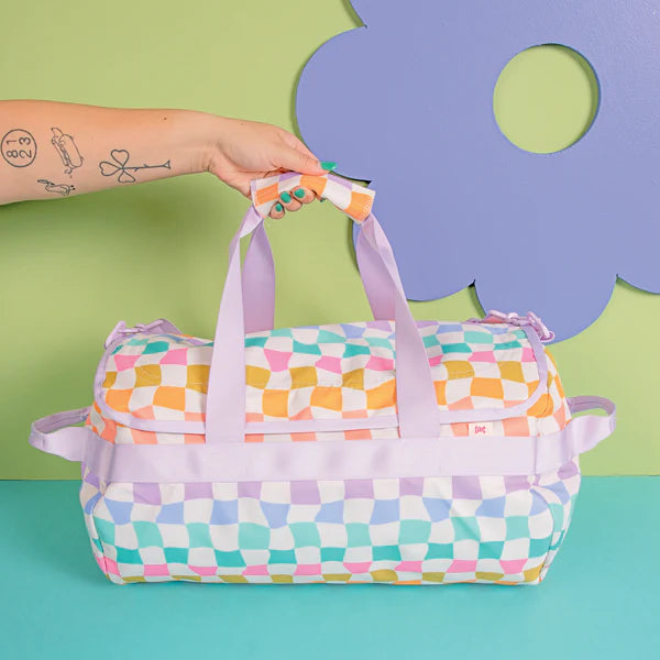 hand holding handles of carnival checkers travel bag.