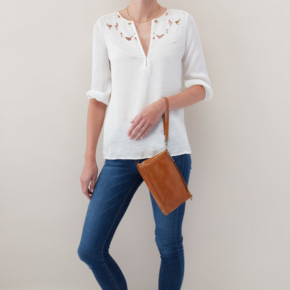 person wearing jeans and a white top with truffle cadence as a wristlet.