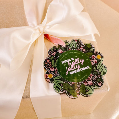 flat scallop edge ornament with pink and green holly imagery tied on a package