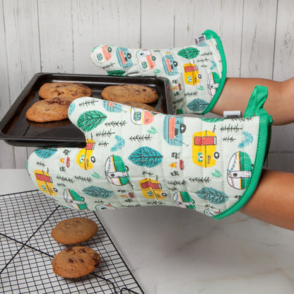 hands wearing RV oven mitts holding a pan of baked cookies.