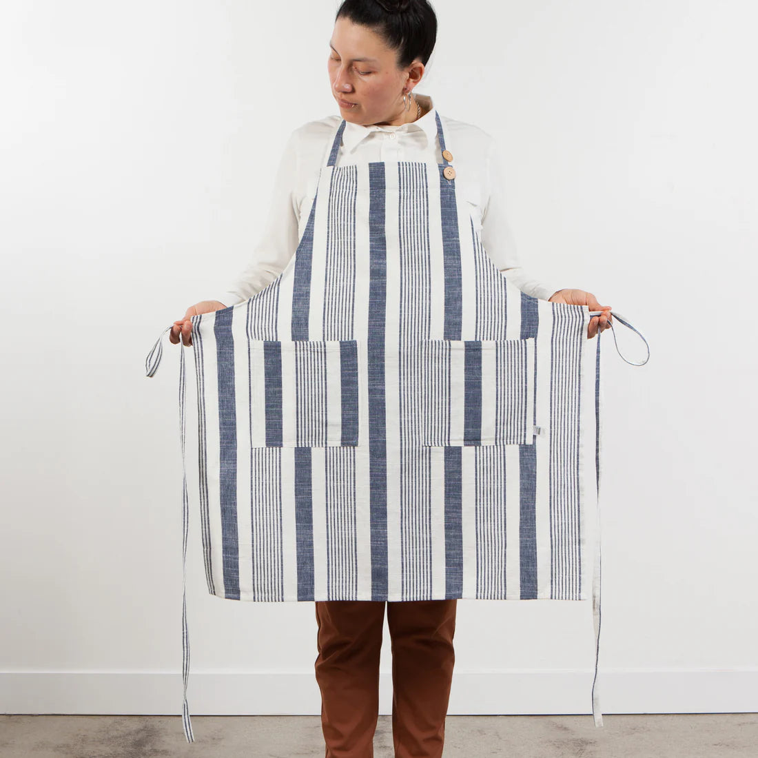 person wearing apron and holding ties out to each side.