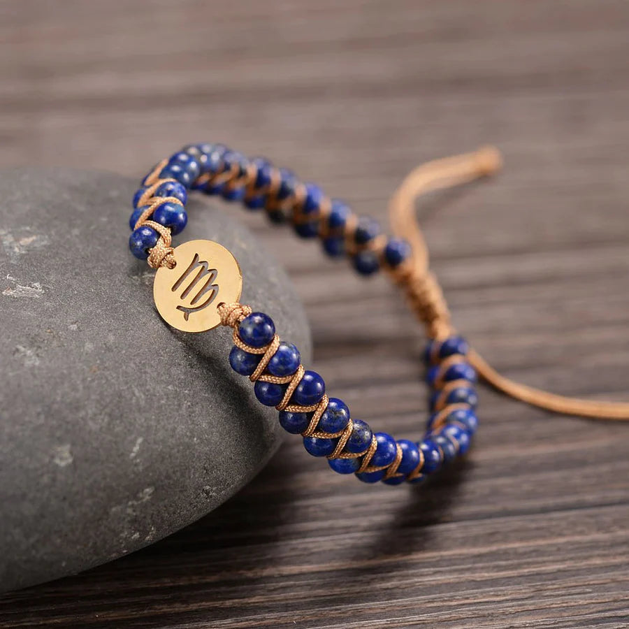 virgo bracelet draped on a stone on a wooden table.