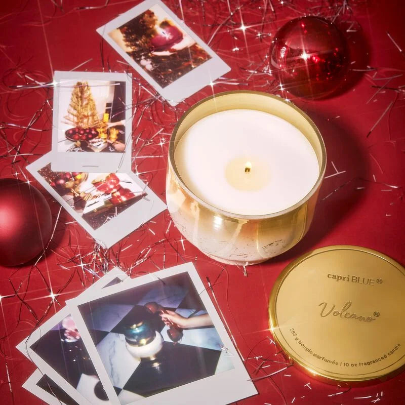 Lit volcano inverted jar candle set on a table with Polaroid pictures and tinsel.