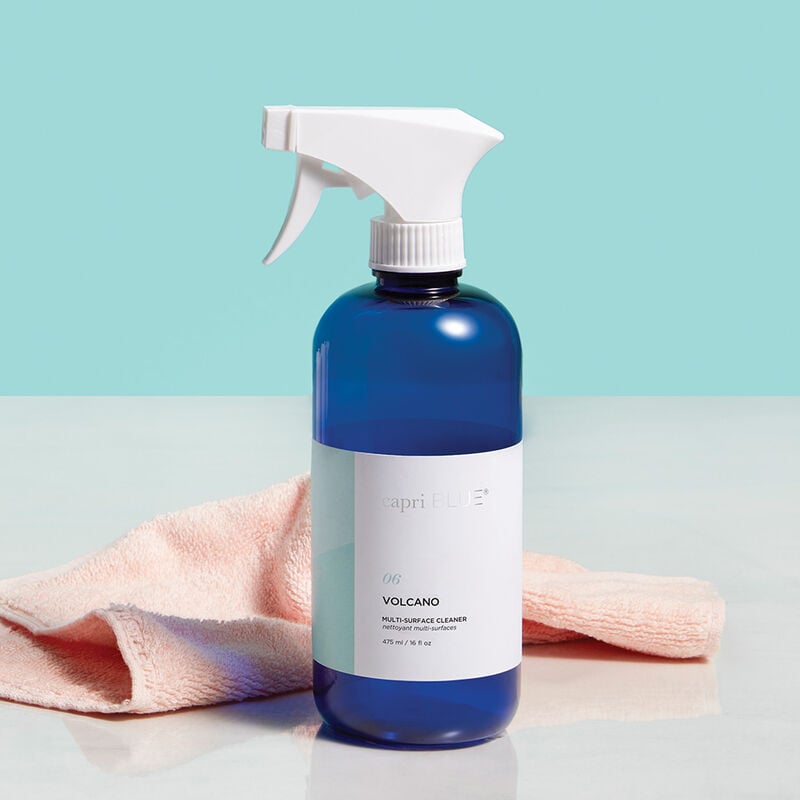 spray bottle of Volcano Multi-Surface Cleaner set on a counter with a peach colored towel.
