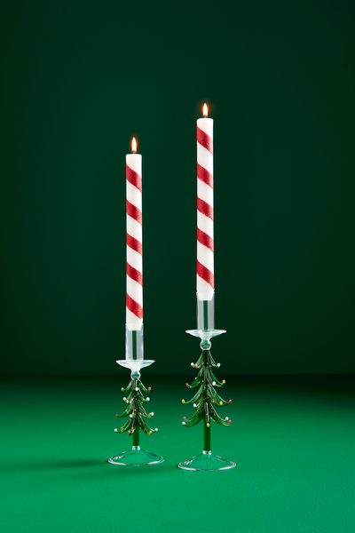 2 glass tree candle holders with red and white striped candles in them.