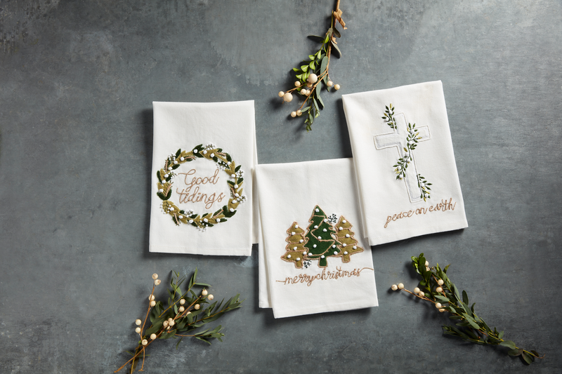 3 styles Of Christmas hand towels with green velvet appliques arranged on a grey surface with sprigs of mistletoe.