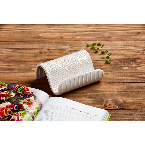 ceramic cookbook holder set on a wooden table with a cookbook.