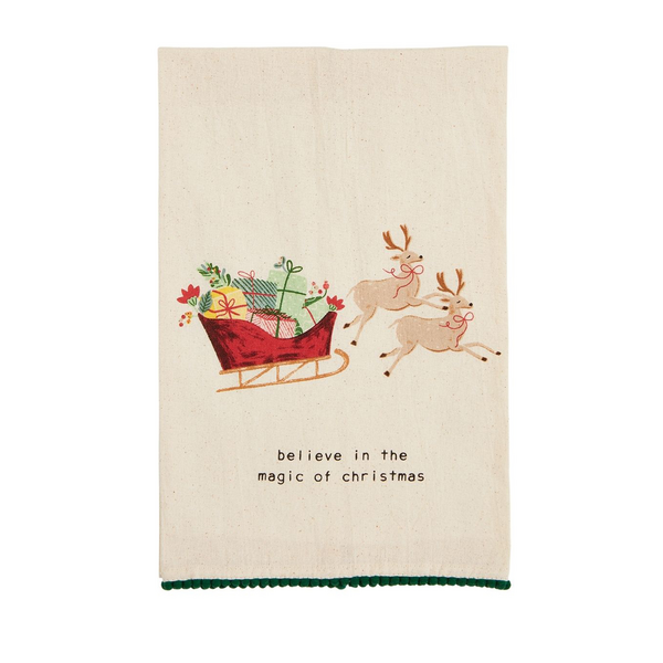 towel printed with a sleigh filled with gifts and pulled by reindeer with "believe in the magic of christmas" printed across the bottom.