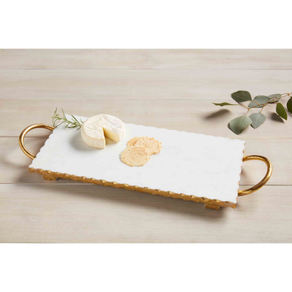 Gold and Marble Board with cheese and crackers on it set on a wood slat surface with a sprig of greenery.