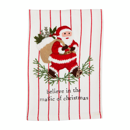 white towel with red striped and santa carrying his sack of presents embroidered on it and 'believe in the magic of christmas" printed along the bottom.