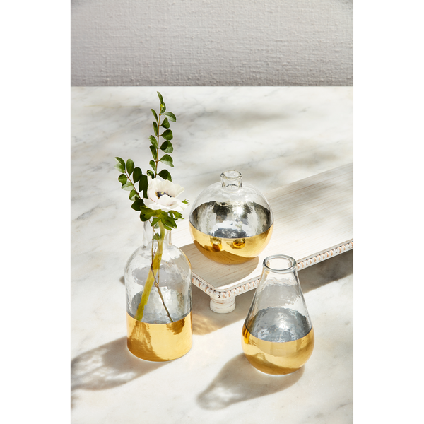 3 sizes of glass and gold vases arranged on a table, large vase has a flower in it.