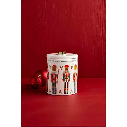 nutcracker cookie jar set on a red table with 2 red ornaments balls.