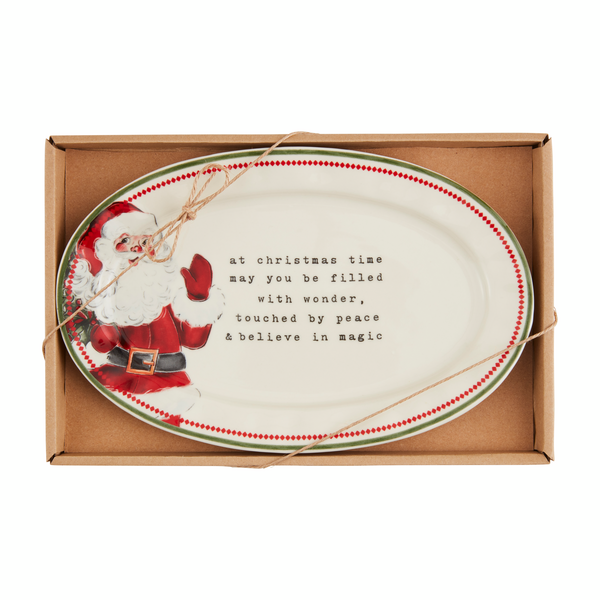 off-white, oval ceramic plate with a waving Santa on the left and "at Christmas time may you be filled with wonder, touched by peace and believe in magic" printed next to him.