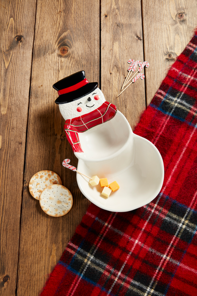 snowman dish with cheese cubes in one section set on a wooden table with a plaid table runner.