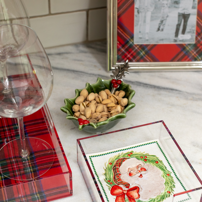 holly bowl filled with pistachios and set on a counter with wine glasses and napkins.