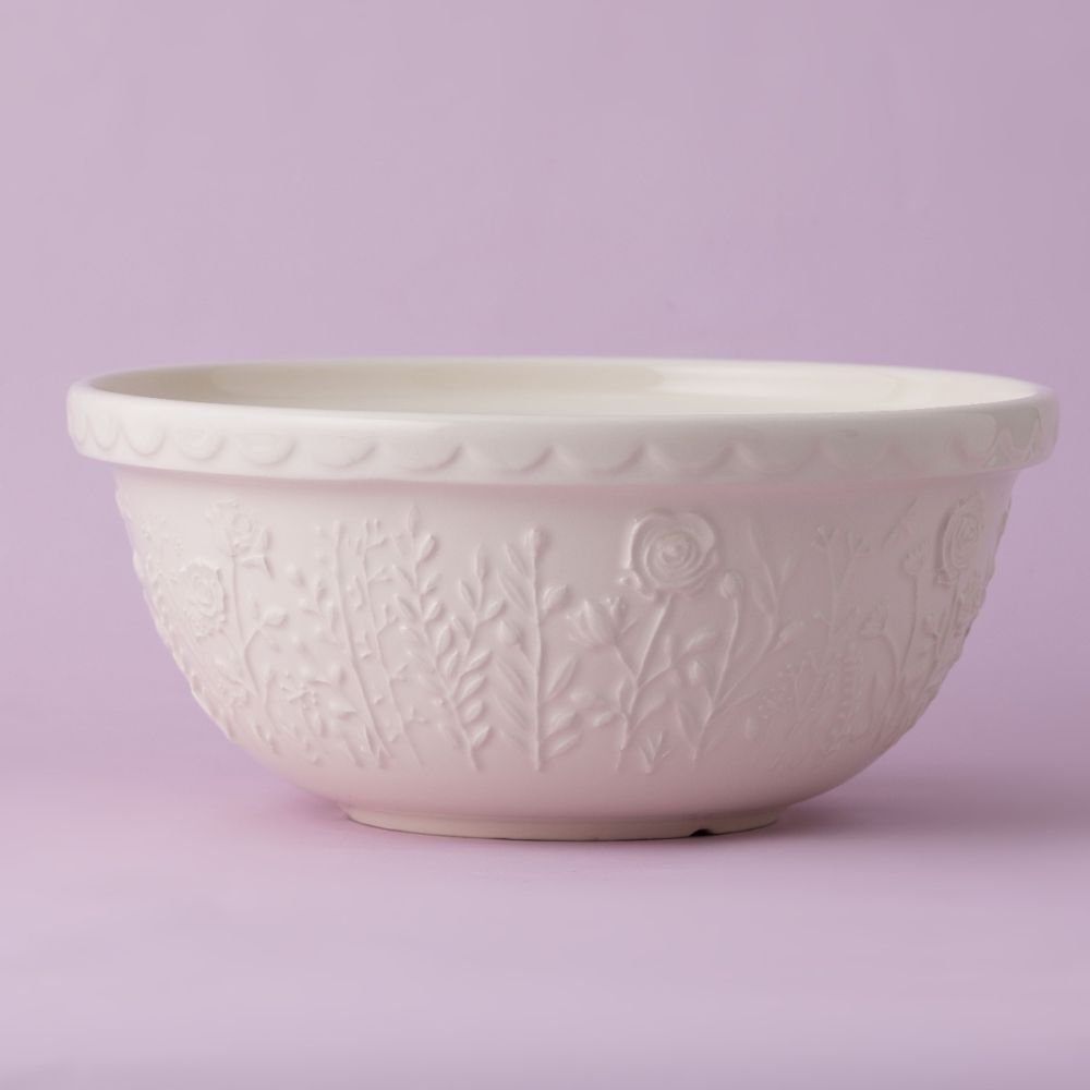 cream colored bowl with embossed floral pattern all around it on a lavender background.