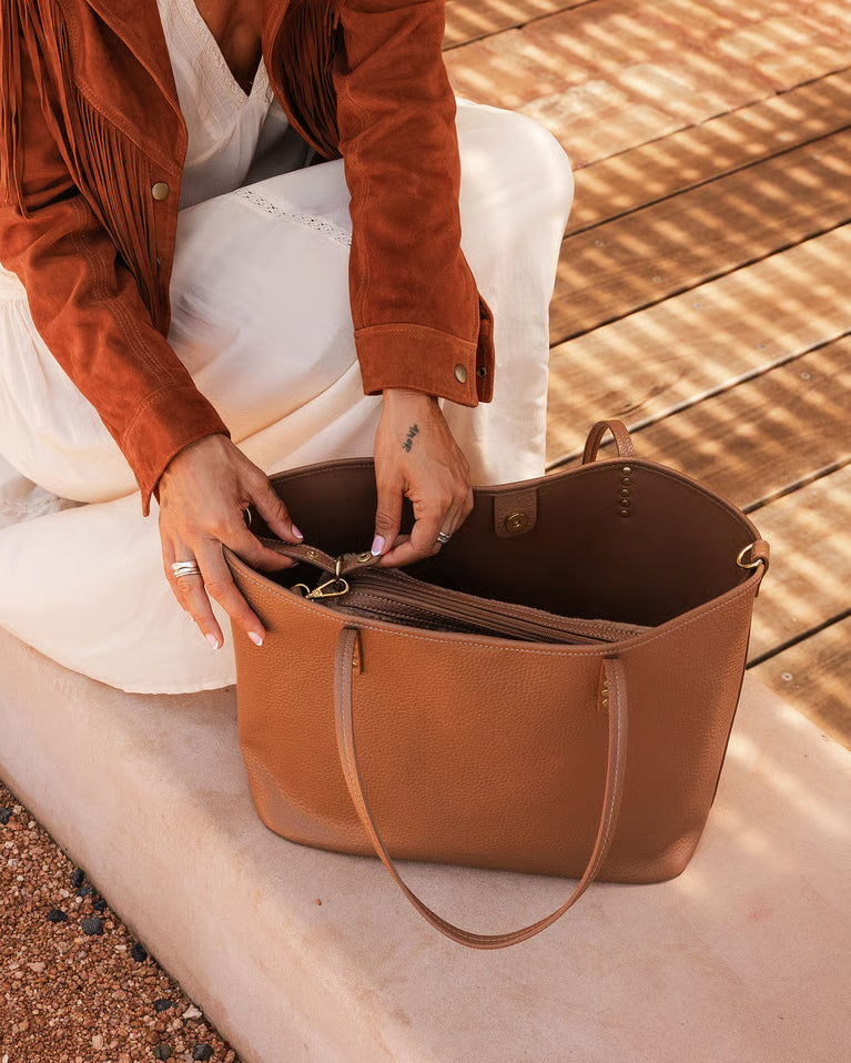 Person opening a brown tote on a wooden deck