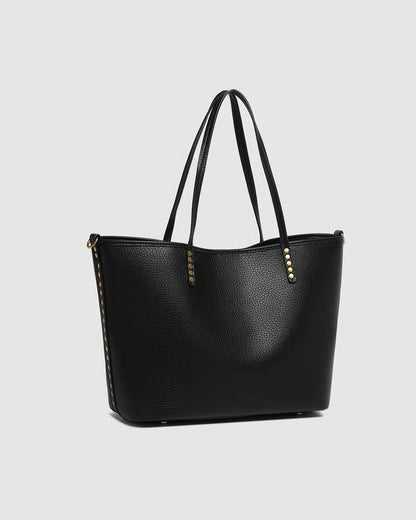 side view of Black tote with gold accents on a light gray background
