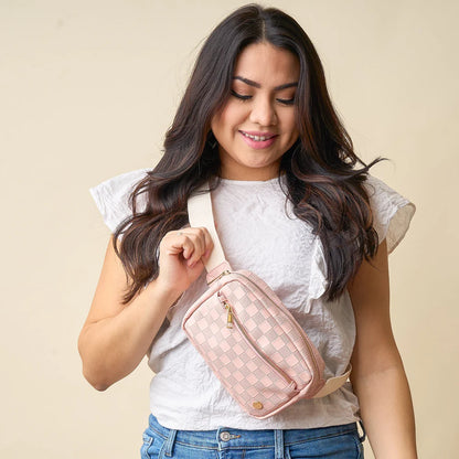 person wearing jeans and a white top with blush Urban Check Belt Bag across their chest.