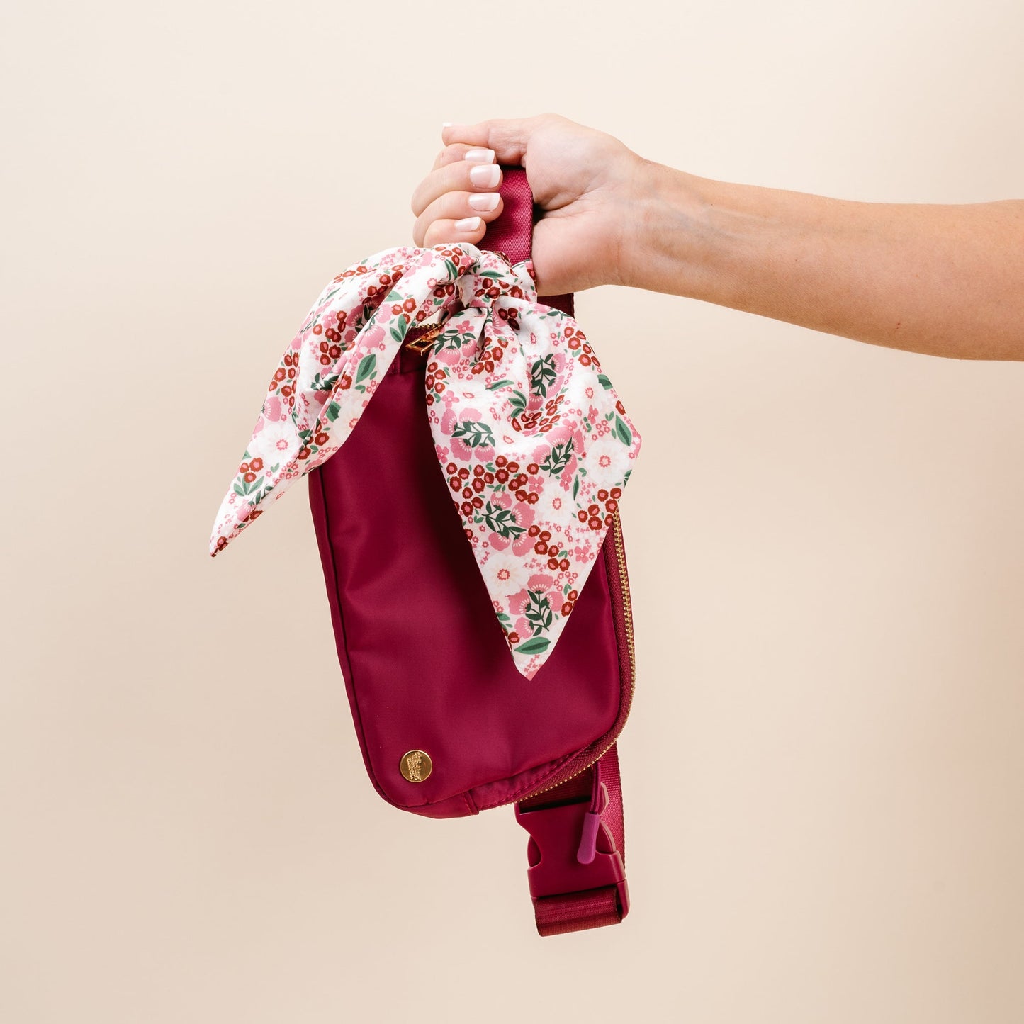 hand holding mulberry all your need bag by the strap on a blush pink background.