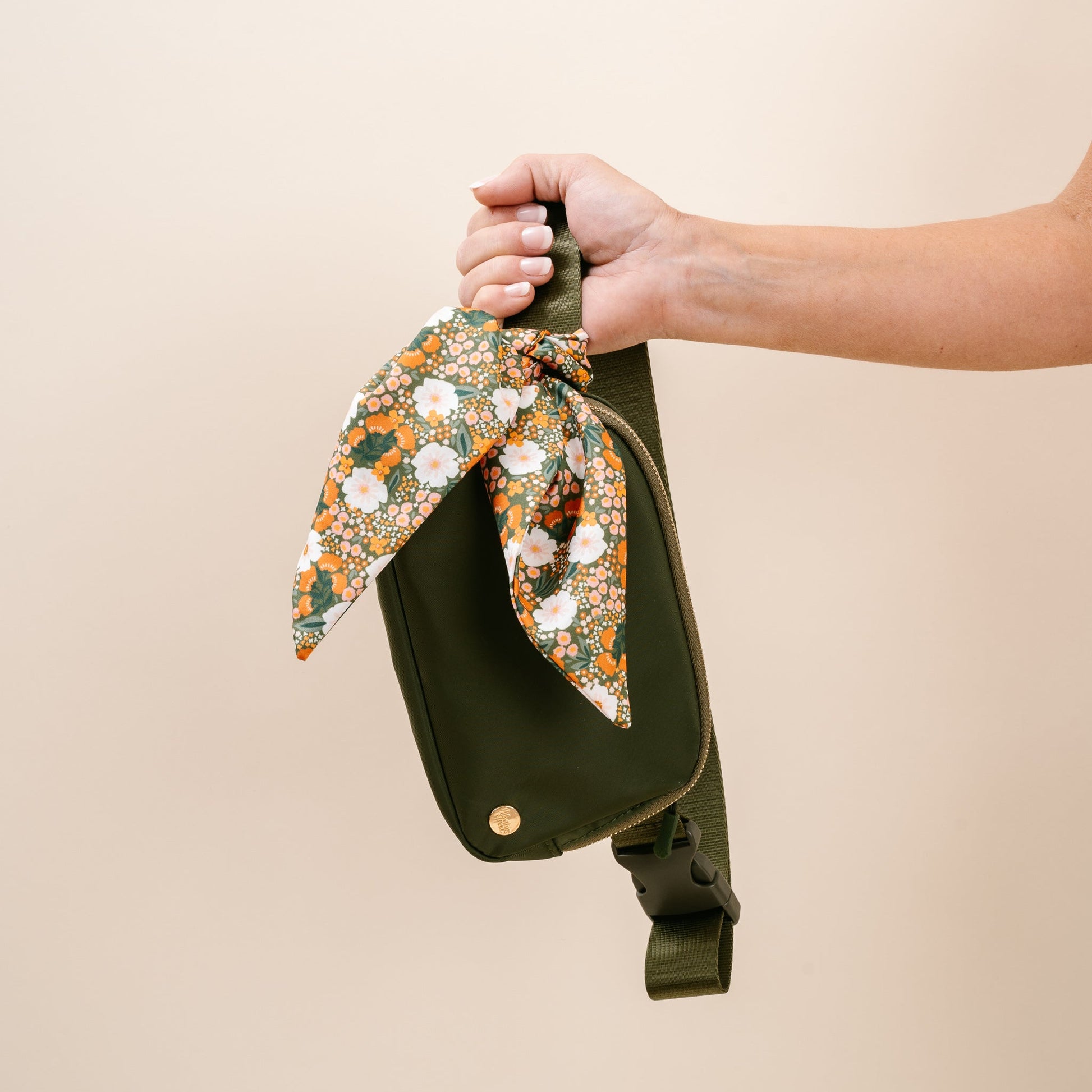 hand holding olive green all your need bag by the strap.