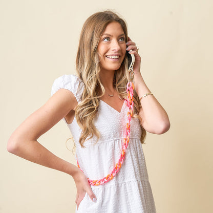 person wearing white dress and talking on their phone attached to sassy phone chain.