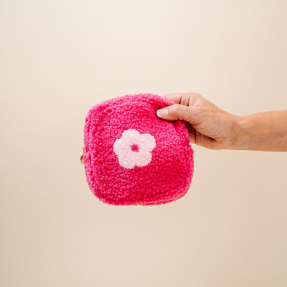 hand holding hot pink sherpa pouch with light pink flower on it.