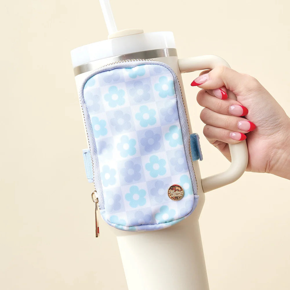 hand holding a tumbler with a blue flower check tumbler fanny pack strapped to it.