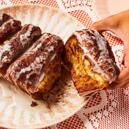 hand reaching for cinnamon roll on a platter