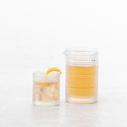 clear jupiter mixing glass and a short glass both filled with beverage and garnish with fruit.