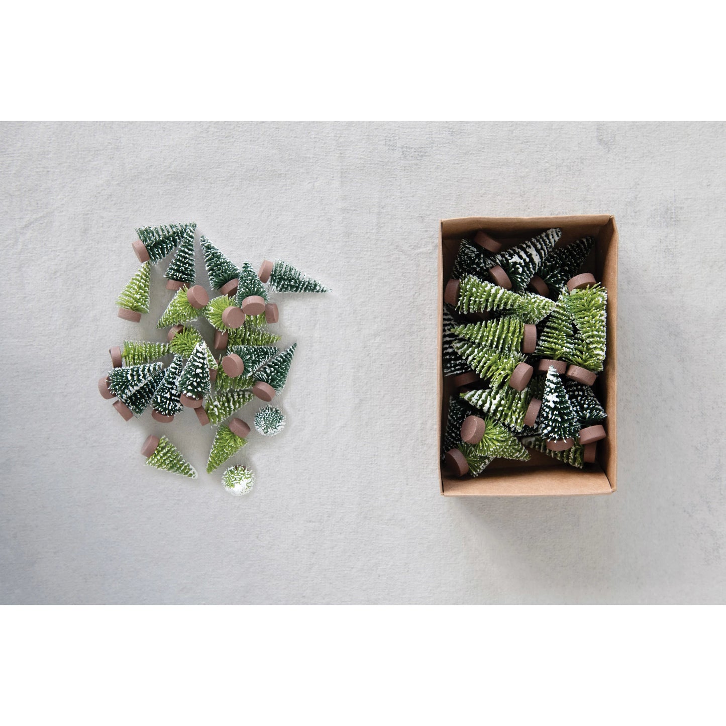 boxed set of mini trees next to a pile of mini trees arranged on a plaster background.