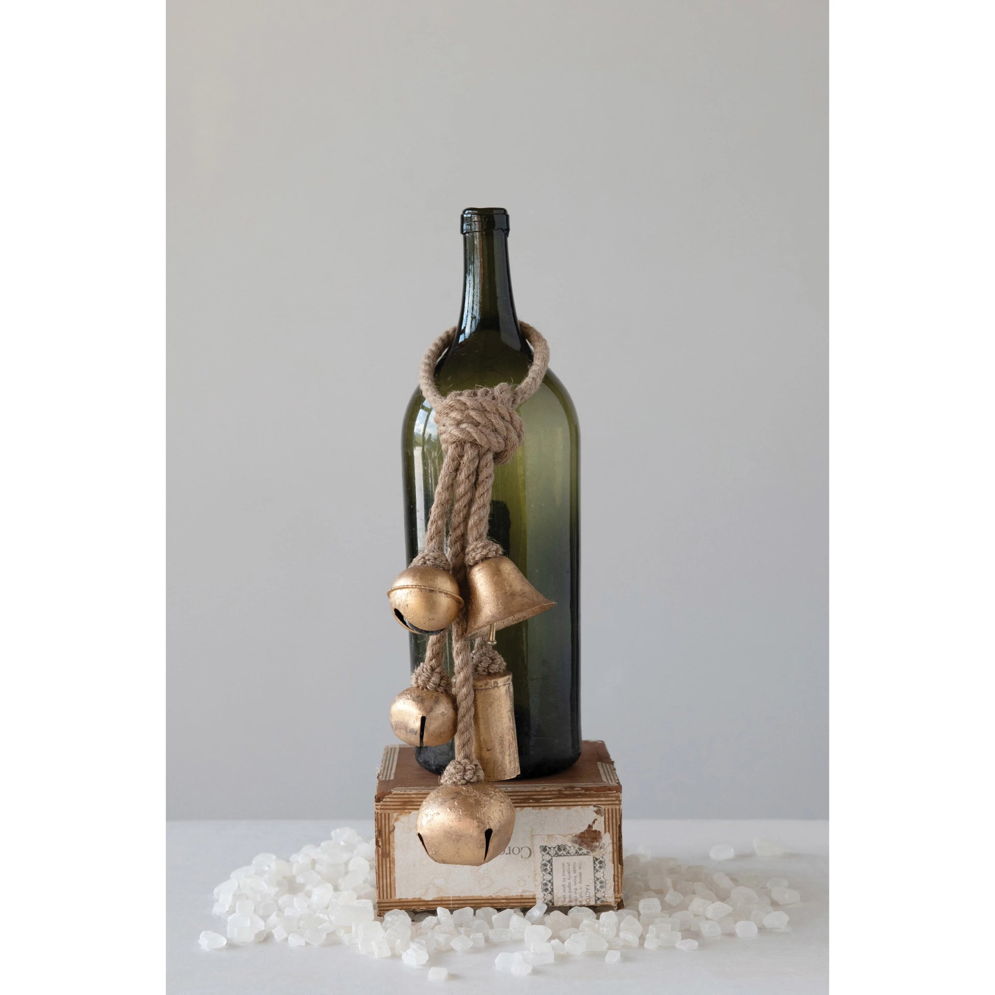 Decorative metal gold bells on a rope hung on a wine bottle set on a table