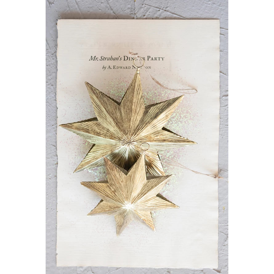 two embossed metal star ornaments displayed on weathered paper