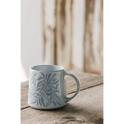 White ceramic mug with blue floral pattern on a wooden surface