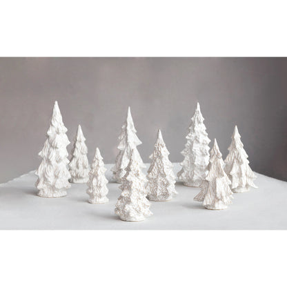 several sizes and shapes of off-white stonware trees arranged on a light grey table.